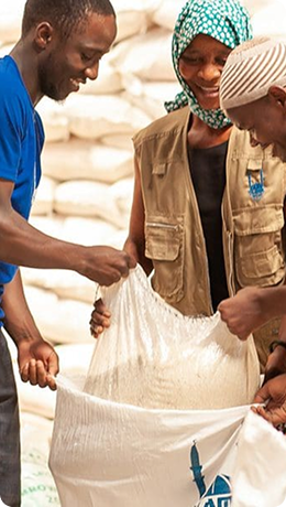 Reeler image of 3 people smiling while handling a sack of goods